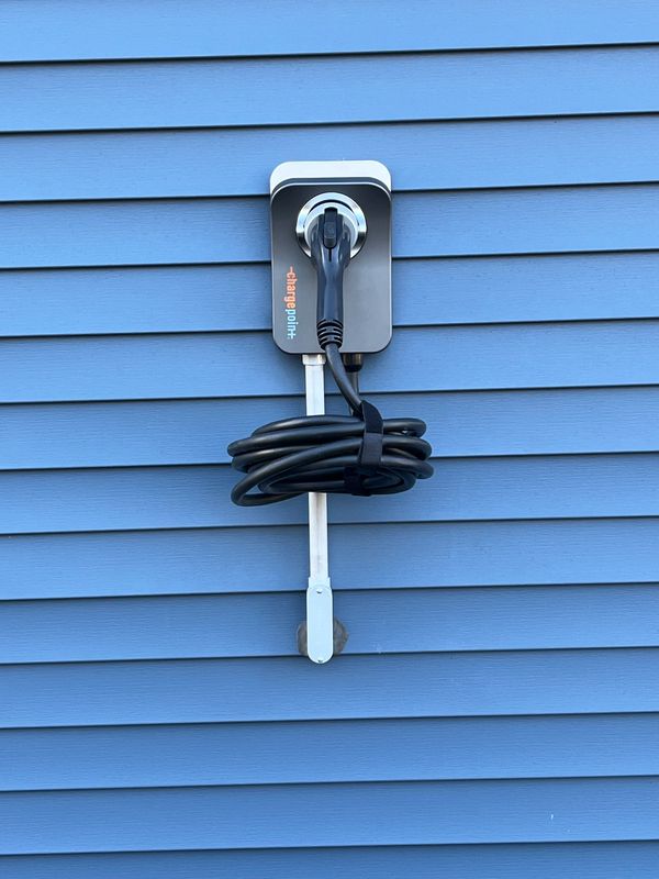 Electric vehicle charging station mounted on blue exterior wall.
