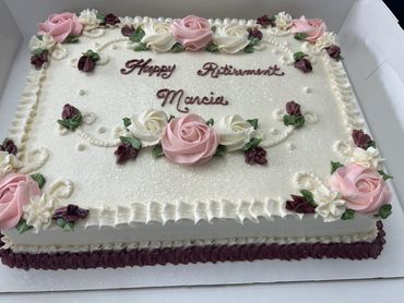 Elegant retirement cake decorated with pink and white roses and a congratulatory message.