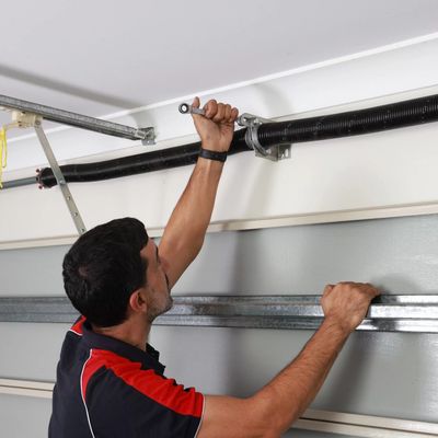 Technician repairing a garage door spring mechanism. Garage Door Spring Replacement in Rochester, NY