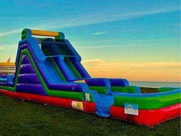 A colorful inflatable water slide set up outdoors near the ocean.