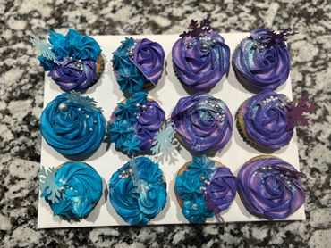 Blue and purple frosted cupcakes with silver beads and snowflake decorations.