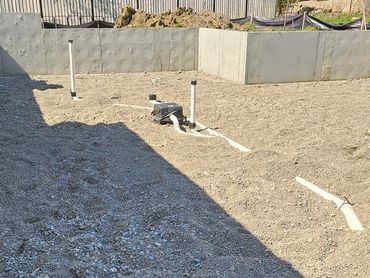 Construction site with gravel and plumbing pipes.