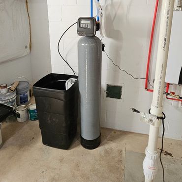 Basement water filtration system with pipes and control unit.