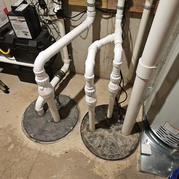 Basement sump pump system with PVC pipes and check valves.
