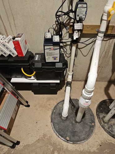 Basement sump pump system with connected pipes and electrical devices.