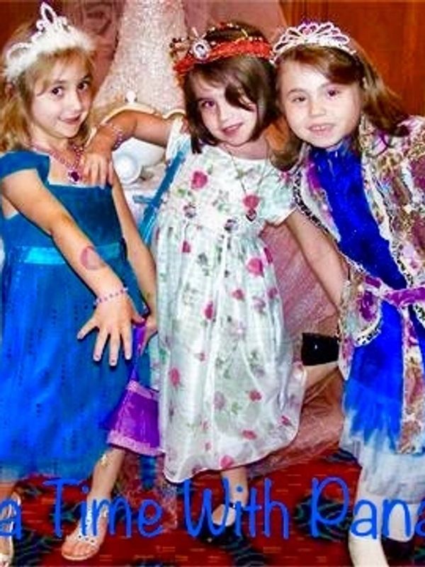 Three young girls dressed as princesses posing happily indoors.