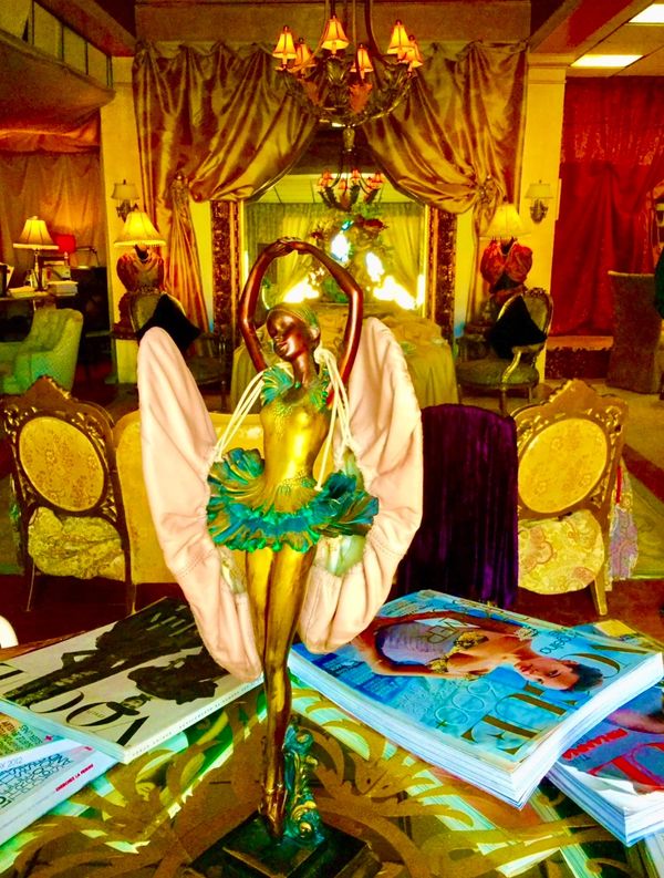 Elegant ballerina statue on a table with fashion magazines in a luxurious room.