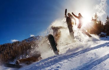 gruppo di ragazzi che va con lo snowboard e salta nella neve delle dolomiti