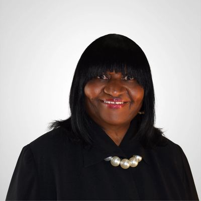Portrait of a smiling woman with black hair and pearl necklace.