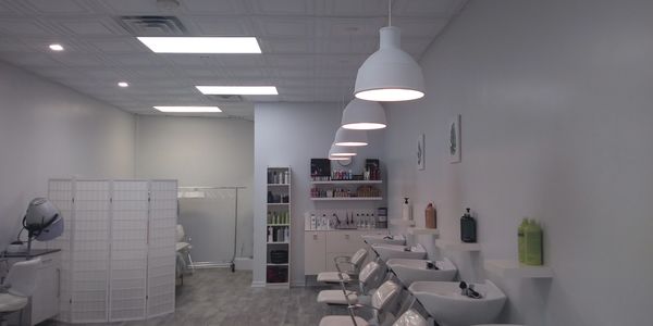 Modern hair salon with white washing stations and shelves of hair products.