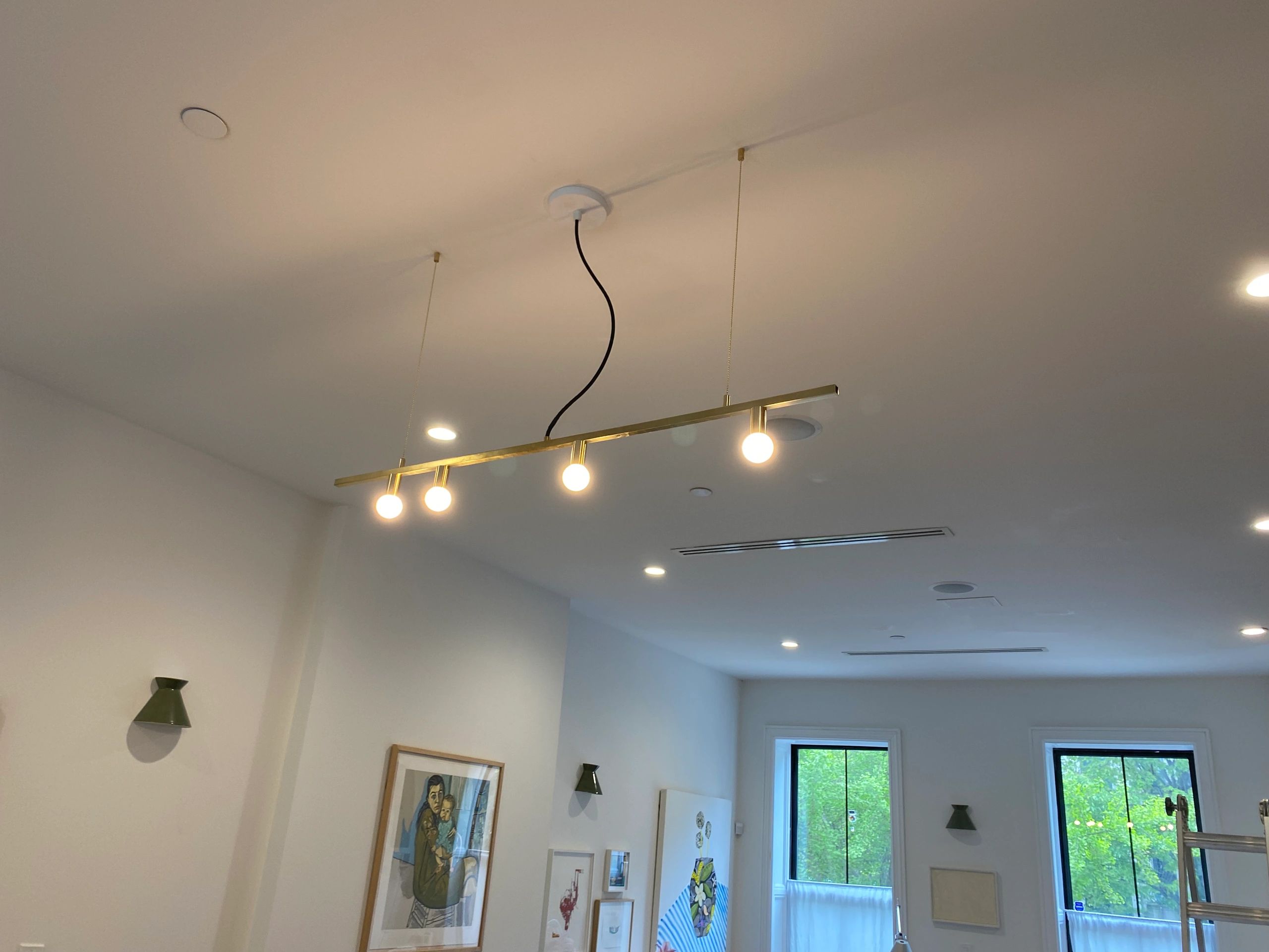 Modern ceiling light fixture with four glowing bulbs in a bright room.