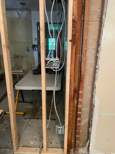 Exposed electrical wiring and metal conduit in a partially demolished wall.