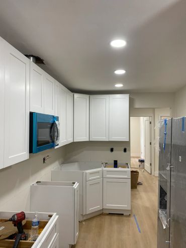 Kitchen under renovation with white cabinets and new appliances.