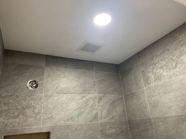 Ceiling light and vent in a tiled room under construction.