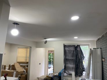 Room under renovation with new ceiling lights and covered window.