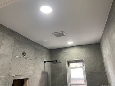 Modern bathroom ceiling with recessed lights and a rainfall showerhead.
