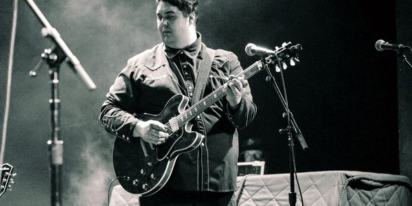 Musician playing electric guitar on stage.