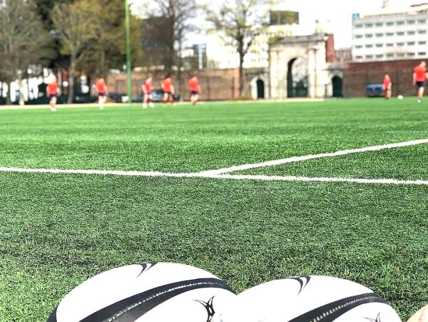 Soccer balls on grass field with players in the background.