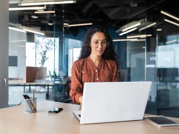 Cheerful and successful Indian woman programmer at work inside modern office,