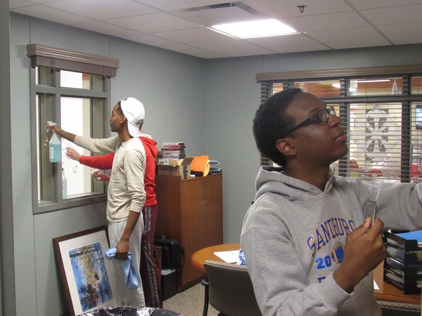 3 ISU students from from Sigma Pi fraternity clean windows in staff office as volunteers at ARC