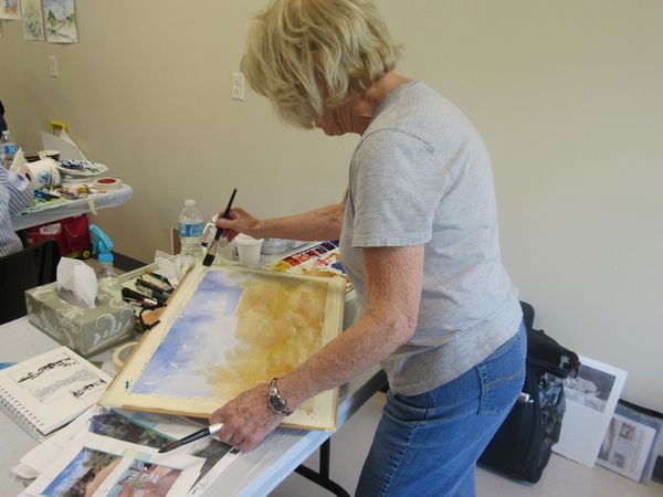 Over-shoulder view of member painting a landscape in watercolor