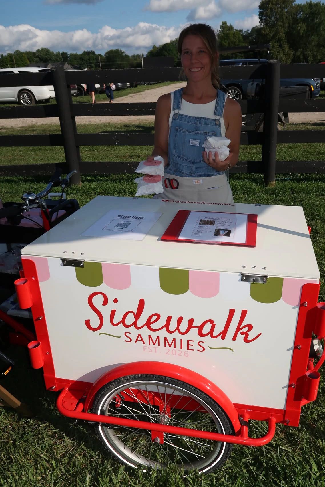 Woman selling sandwiches from Sidewalk Sammies cart.