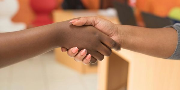 Two people shaking hands in an office setting.