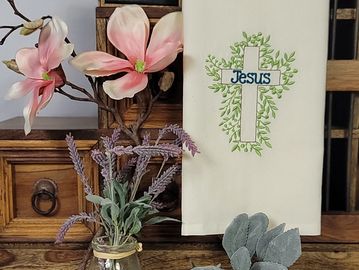 Decorative floral arrangement with a towel featuring a cross and the word Jesus.