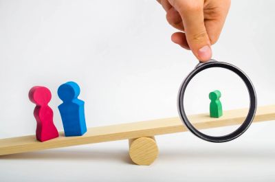 Magnifying glass focusing on a small green figure on a seesaw with two larger figures.