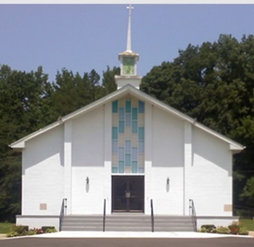 White church with a tall steeple and stained glass windows.