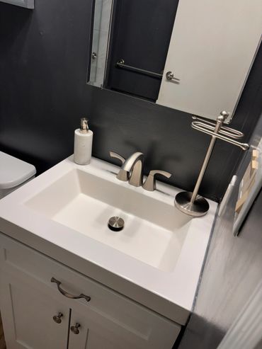 Modern bathroom sink with black walls and silver fixtures.