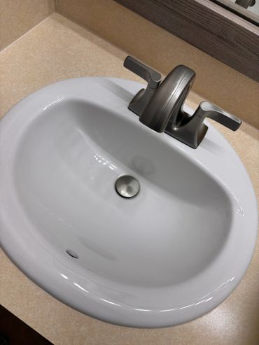 Clean white bathroom sink with modern metal faucet.