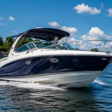 A sleek motorboat cruising on calm water under a partly cloudy sky.