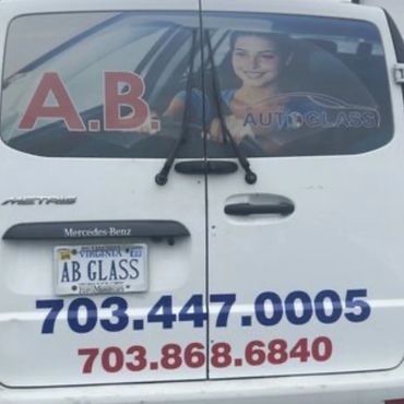 A van advertising A.B. Autoglass with two phone numbers and a smiling woman image.