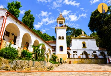 Iglesia blanca con torre bajo cielo azul y árboles.