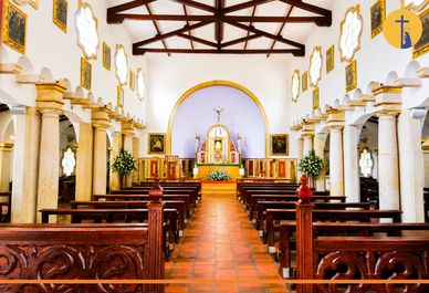 Interior de una iglesia con bancos de madera y altar.