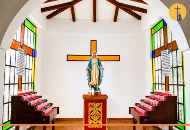 Interior de capilla con estatua religiosa y vitrales de colores.