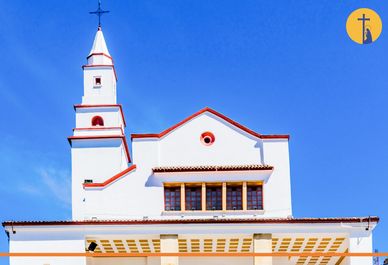 Iglesia blanca con detalles rojos bajo un cielo azul.