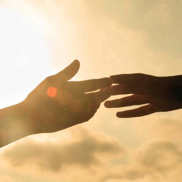 Deux mains qui se joignent sur le soleil en arrière-plan