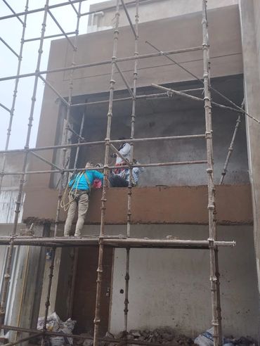 Workers plastering a building facade using scaffolding.