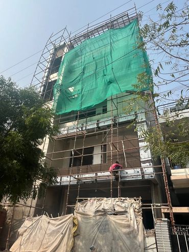 Building under construction with scaffolding and a worker installing panels.