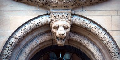 Sandstone gargoyle face in arch