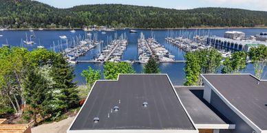 A marina filled with numerous docked sailboats surrounded by greenery and hills.