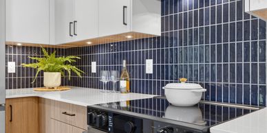 Modern kitchen corner with blue tile backsplash and white countertop.