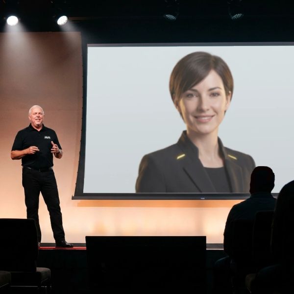 Man presenting with a large screen showing a businesswoman.