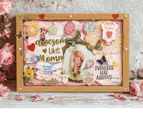 A framed shadowbox keepsake baby announcement with pink decorations and a newborn photo.