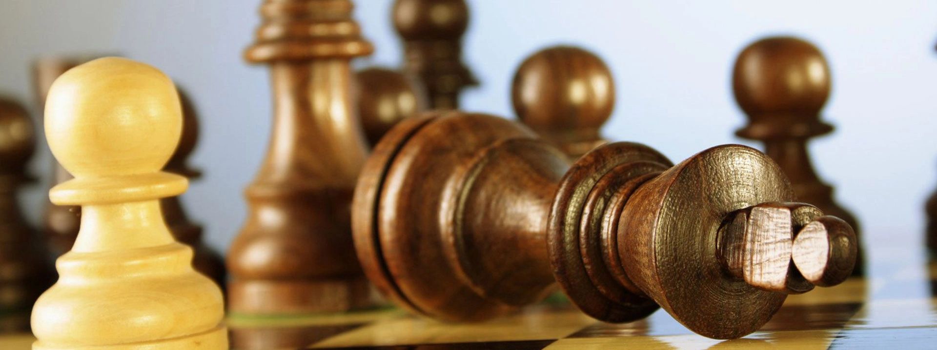 A fallen black king chess piece on a chessboard.