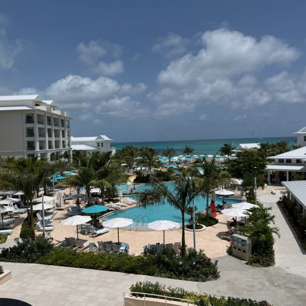 Resort pool area with umbrellas and ocean view.