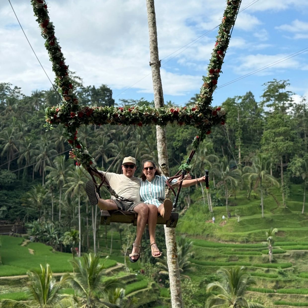 Couple enjoying a swing with a green terraced background.