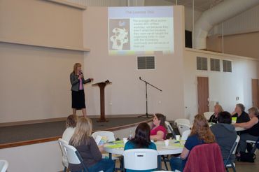 a woman standing at a podium in front of a group of people